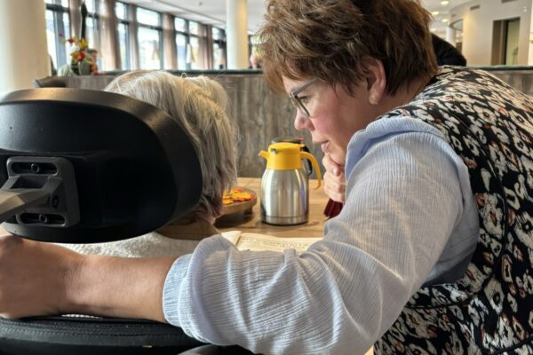 Krant lezen samen met cliënt in de huiskamer